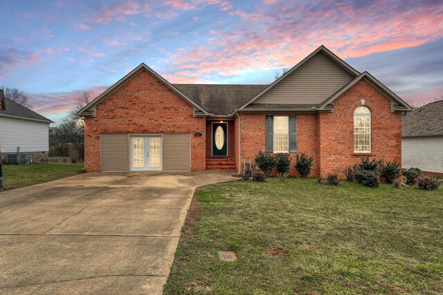 view of property featuring cooling unit, a lawn, and french doors