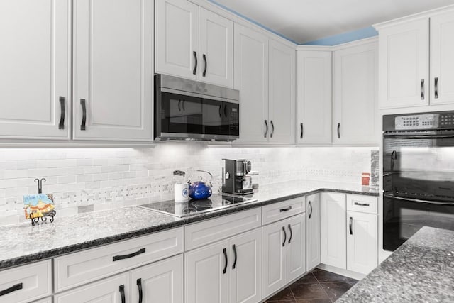 kitchen with tasteful backsplash, black appliances, dark stone counters, and white cabinets