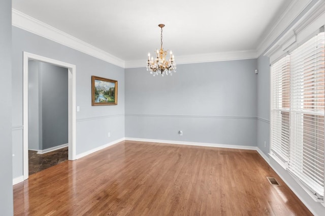 empty room with ornamental molding, a chandelier, and wood-type flooring