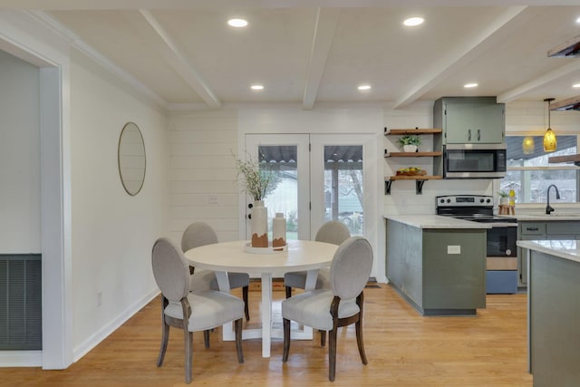 dining area with sink, light hardwood / wood-style flooring, beamed ceiling, and plenty of natural light