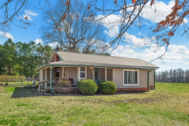 exterior space featuring metal roof, a porch, a chimney, and a front yard