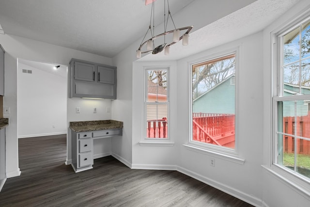 unfurnished dining area with dark hardwood / wood-style flooring, built in desk, and a textured ceiling