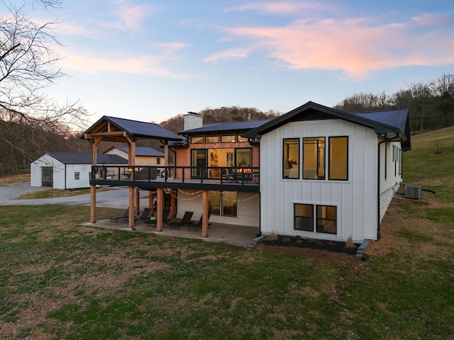 back house at dusk with cooling unit, a yard, a gazebo, and a patio area