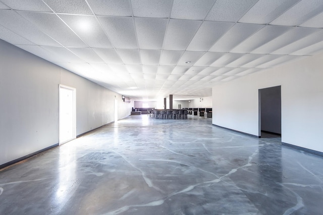 interior space featuring a drop ceiling, baseboards, and concrete flooring