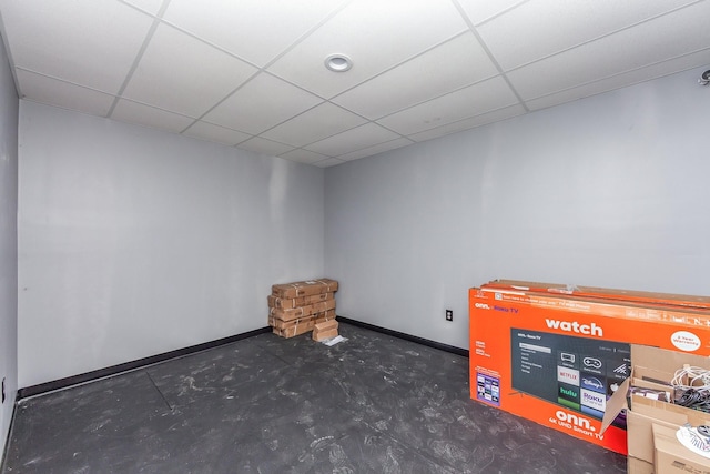 interior space with concrete flooring, a paneled ceiling, and baseboards