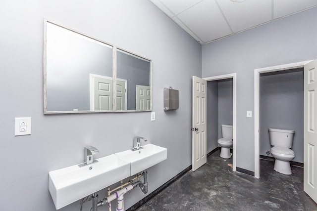 full bath with baseboards, a paneled ceiling, toilet, and concrete flooring