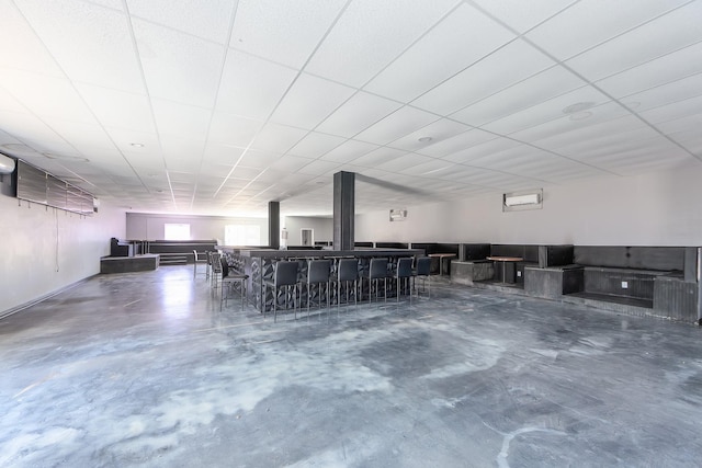 miscellaneous room featuring a paneled ceiling and concrete floors