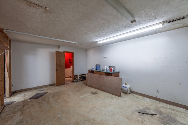 below grade area featuring visible vents, a textured ceiling, and baseboards