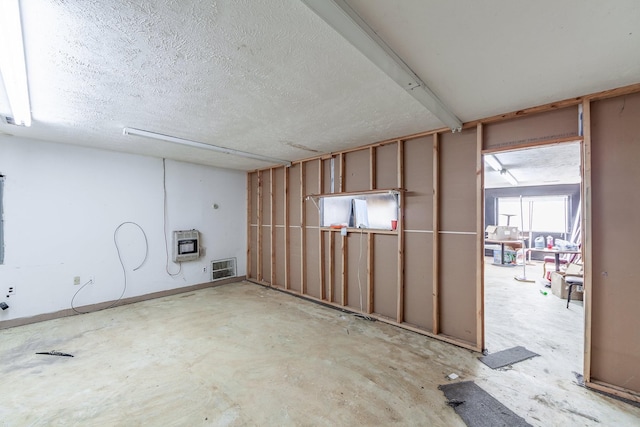 basement featuring heating unit and a textured ceiling