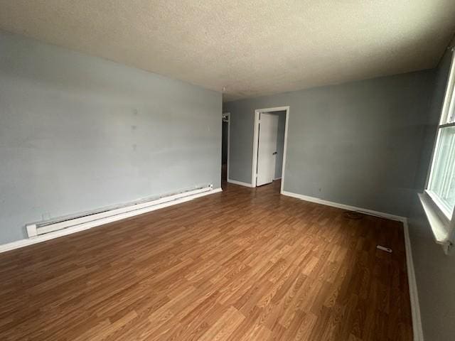 unfurnished room featuring hardwood / wood-style flooring, a textured ceiling, and baseboard heating