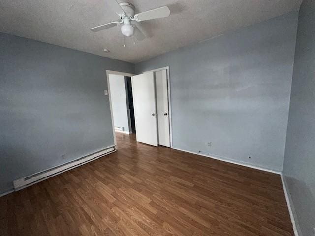 empty room with ceiling fan, dark hardwood / wood-style floors, a textured ceiling, and a baseboard heating unit