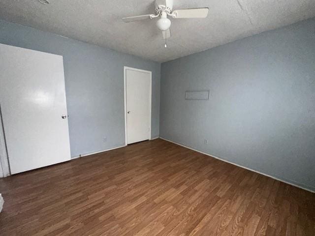 unfurnished bedroom featuring ceiling fan, dark wood-type flooring, and a textured ceiling