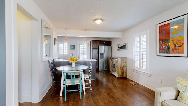 dining space with dark wood-style floors, visible vents, and baseboards