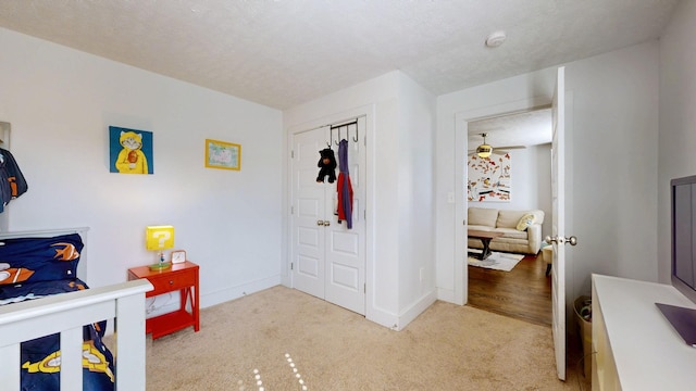 bedroom with light carpet, a textured ceiling, and baseboards