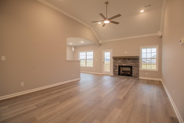 unfurnished living room with a stone fireplace, high vaulted ceiling, hardwood / wood-style flooring, ceiling fan, and crown molding