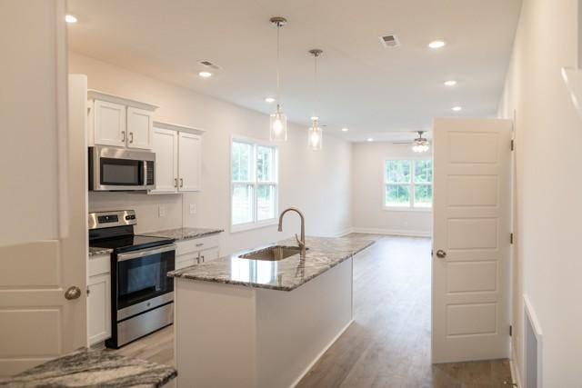 kitchen with sink, white cabinetry, a center island with sink, pendant lighting, and stainless steel appliances