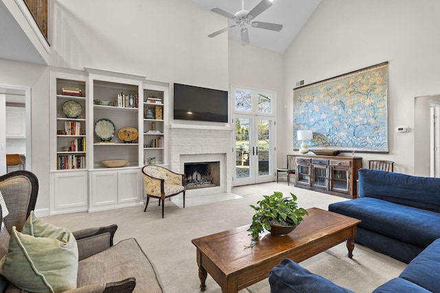 living room with french doors, light colored carpet, high vaulted ceiling, ceiling fan, and a fireplace