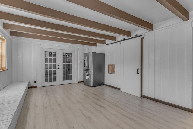 interior space with french doors, a barn door, light wood-type flooring, and beamed ceiling