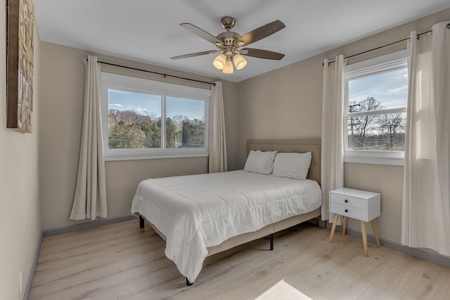bedroom featuring ceiling fan, multiple windows, and light wood-type flooring