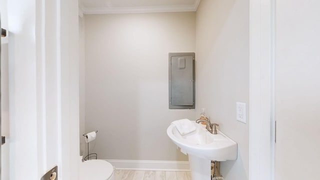 half bath featuring ornamental molding, baseboards, toilet, and wood finished floors