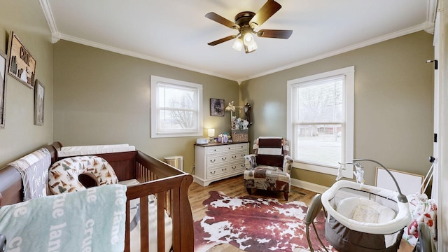 bedroom with ceiling fan, ornamental molding, light wood-style flooring, and baseboards