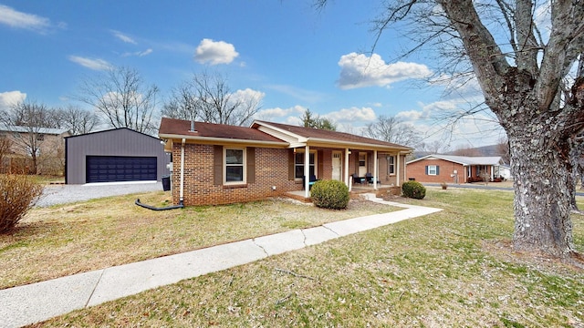 ranch-style home with an outbuilding, brick siding, covered porch, a front yard, and a garage