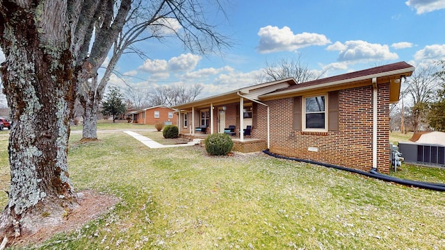 back of property with covered porch, brick siding, and a lawn