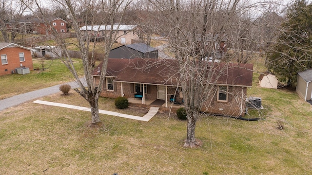 view of front of house with a front yard, cooling unit, and brick siding