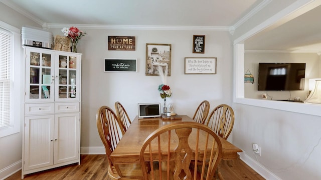 dining room featuring baseboards, wood finished floors, and crown molding