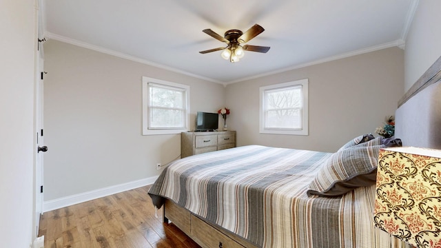 bedroom with ornamental molding, multiple windows, wood finished floors, and baseboards