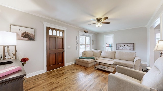 living room with ornamental molding, light wood finished floors, a ceiling fan, and baseboards