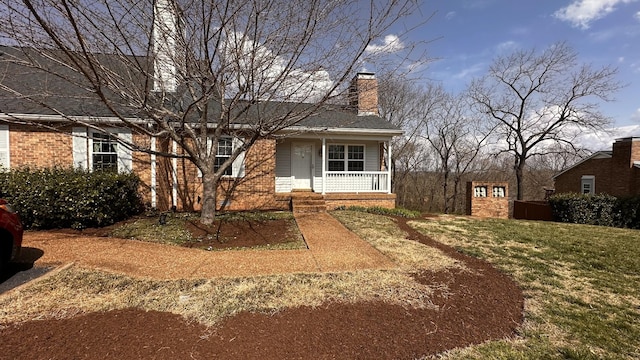 view of front of home with a porch, brick siding, a front yard, and a chimney