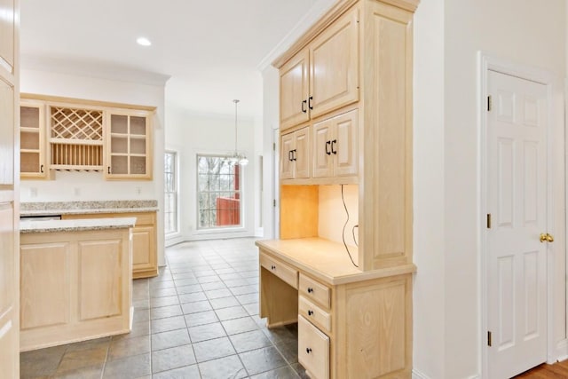 kitchen featuring light brown cabinets, glass insert cabinets, light stone countertops, ornamental molding, and tile patterned floors