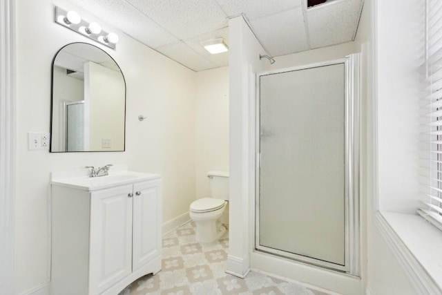full bathroom featuring vanity, a stall shower, a paneled ceiling, tile patterned floors, and toilet