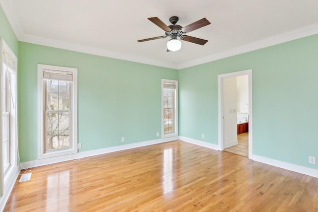 empty room with visible vents, ornamental molding, a ceiling fan, wood finished floors, and baseboards