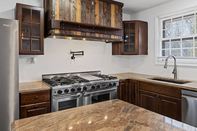 kitchen featuring light stone counters, stainless steel appliances, sink, and dark brown cabinets