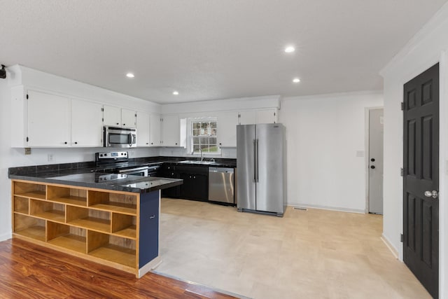 kitchen with sink, appliances with stainless steel finishes, ornamental molding, white cabinets, and kitchen peninsula