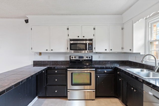 kitchen with appliances with stainless steel finishes, sink, white cabinets, and a textured ceiling