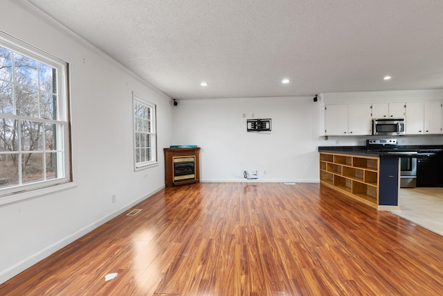 unfurnished living room featuring hardwood / wood-style flooring and a textured ceiling