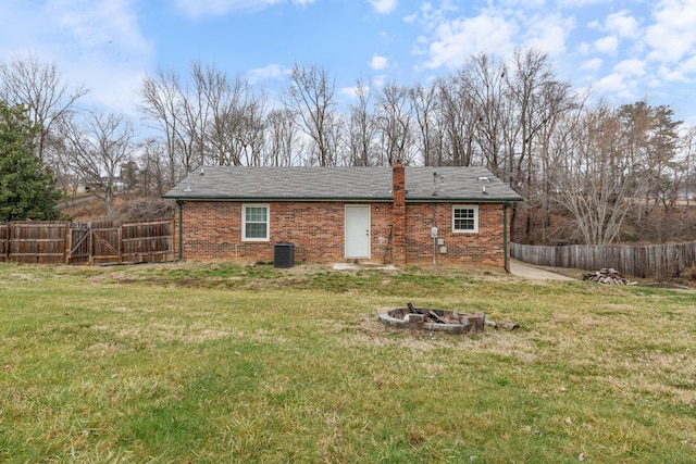 back of property featuring central AC, an outdoor fire pit, and a lawn