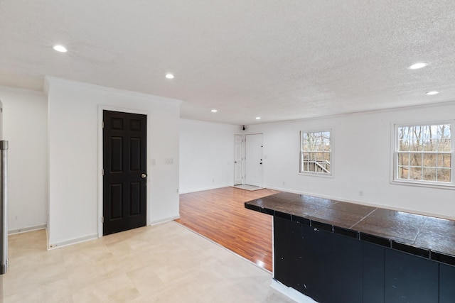 kitchen with ornamental molding, light hardwood / wood-style floors, and a textured ceiling