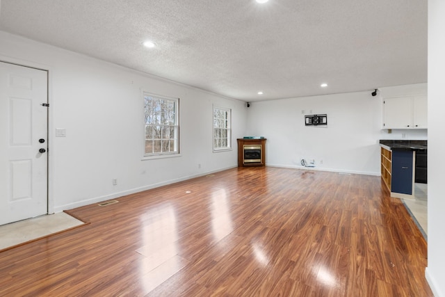 unfurnished living room featuring hardwood / wood-style flooring and a textured ceiling