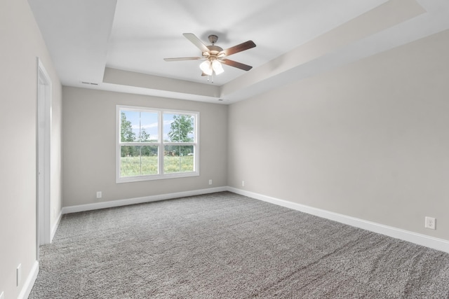 carpeted empty room featuring ceiling fan and a tray ceiling