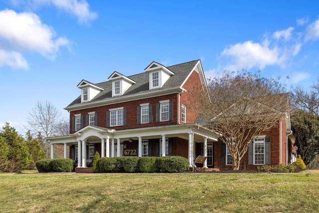 colonial home featuring a front yard and covered porch