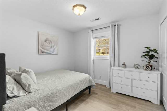 bedroom featuring light hardwood / wood-style flooring and a textured ceiling