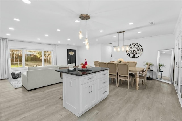 kitchen featuring a center island, white cabinets, light wood-type flooring, and decorative light fixtures