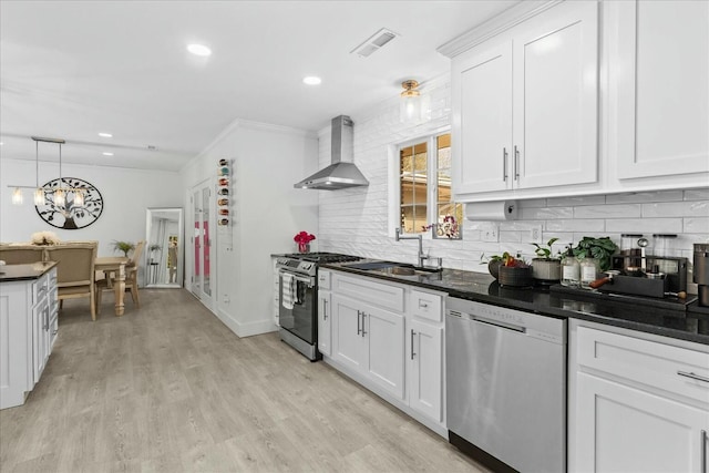 kitchen featuring sink, white cabinetry, light wood-type flooring, stainless steel appliances, and wall chimney range hood