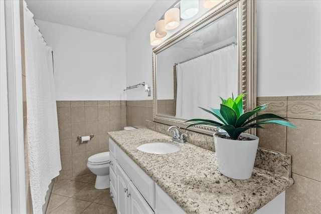 bathroom with tile walls, vanity, tile patterned floors, and toilet