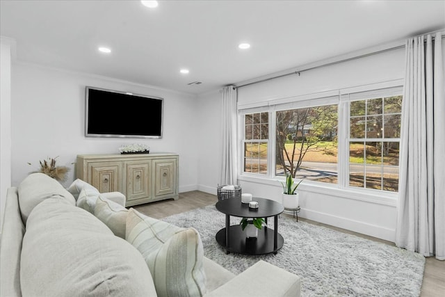 living room with ornamental molding and light hardwood / wood-style floors