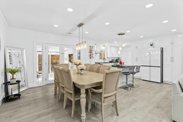 dining space featuring crown molding, french doors, and light wood-type flooring